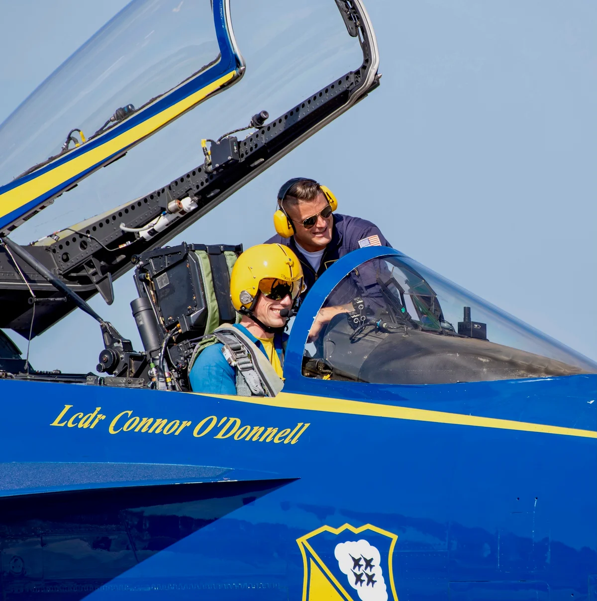 Blue Angels pilot in the cockpit with the canopy open and a crew member alongside